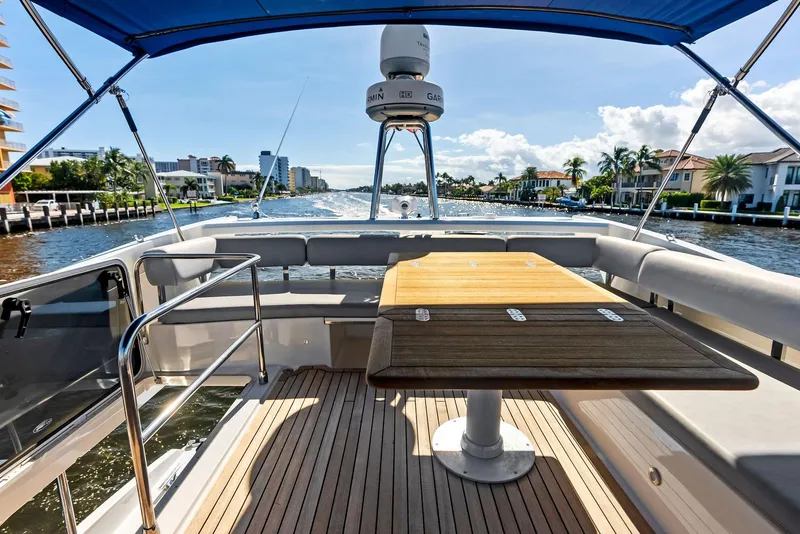 Slide: The Image of Flybridge view of 2013 Absolute 55 FLY yacht with wooden table and waterfront scenery. - 28