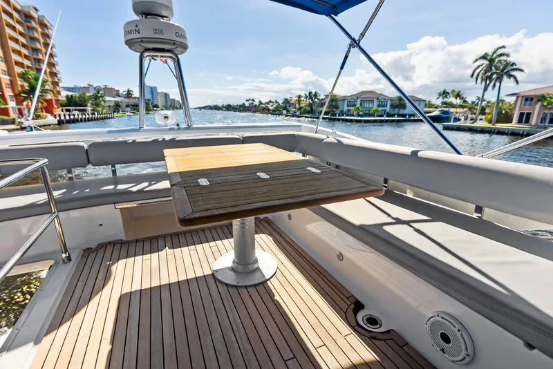 Slide: The Image of Luxury Absolute 55 FLY yacht deck with wooden table, scenic waterfront view. - 33