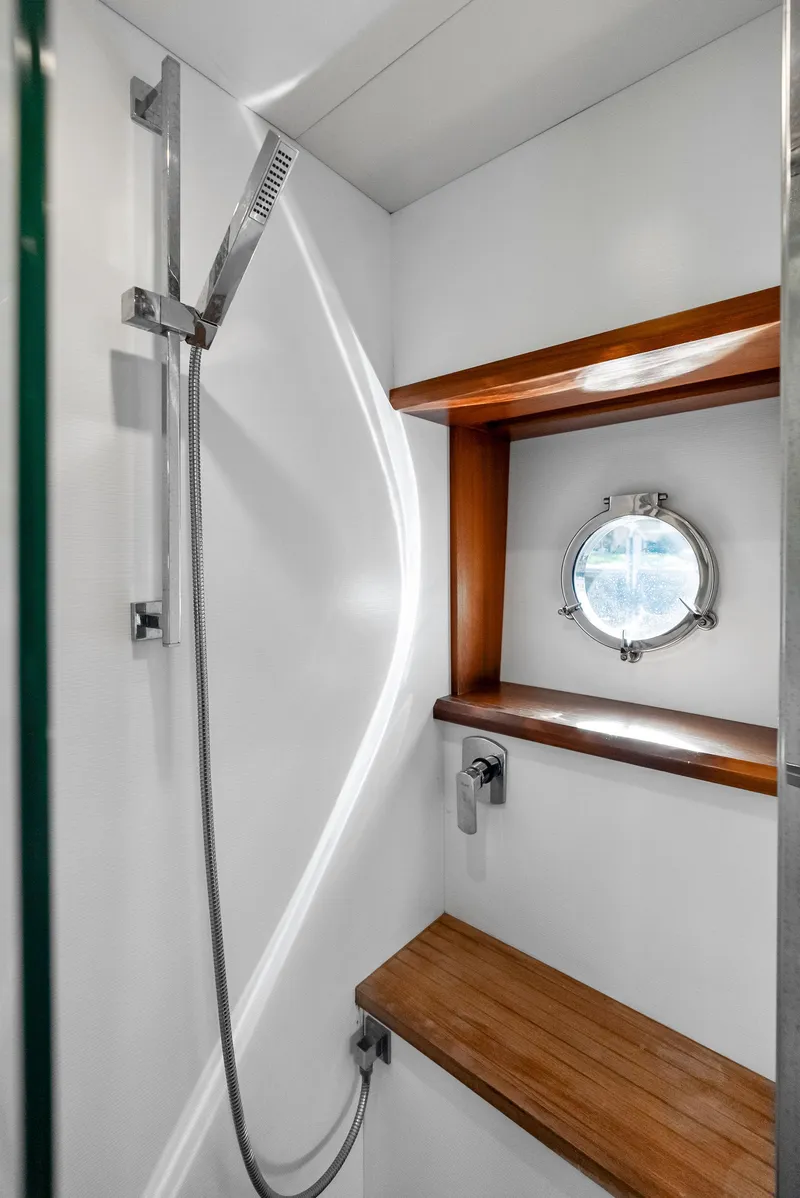 Slide: The Image of Luxurious shower area on 2013 Absolute 55 FLY yacht with wooden shelves and porthole. - 42