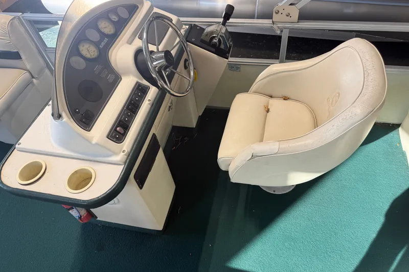 Slide: The Image of Captain's chair and helm of a 1999 Crest II boat with steering wheel and controls. - 13