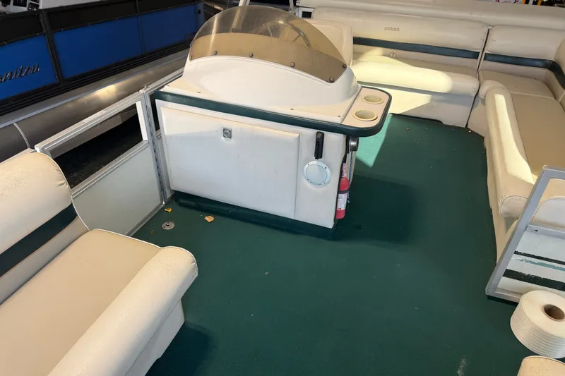 Slide: The Image of Interior of a 1999 Crest II pontoon boat with beige seating and green carpet. - 9