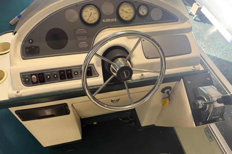 Slide: The Image of 1999 Crest II boat dashboard with steering wheel and control panel. - 14