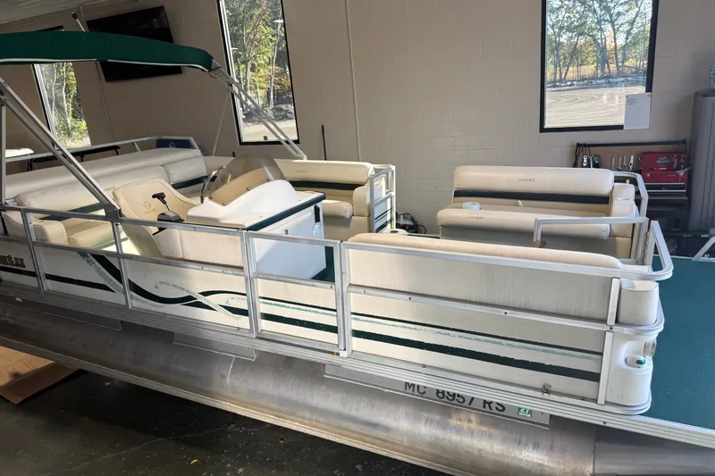Slide: The Image of 1999 Crest II pontoon boat with white seating and green canopy in a garage setting. - 5