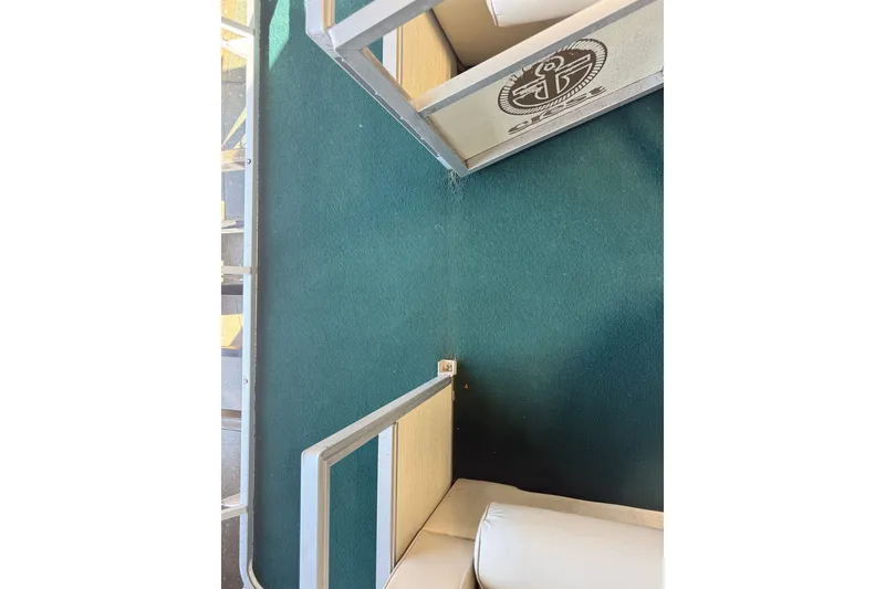Slide: The Image of Interior of a 1999 Crest II boat with green carpet and white seating. - 10