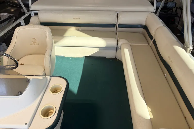 Slide: The Image of Interior of a 1999 Crest II boat with beige seating and green carpet. - 12