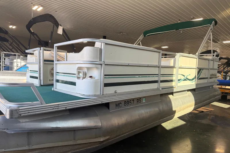 The Image of 1999 Crest II pontoon boat with green accents in indoor showroom. - 0