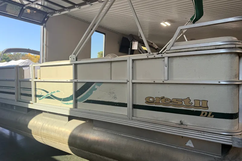 Slide: The Image of 1999 Crest II pontoon boat in a garage, showcasing side view and logo details. - 1