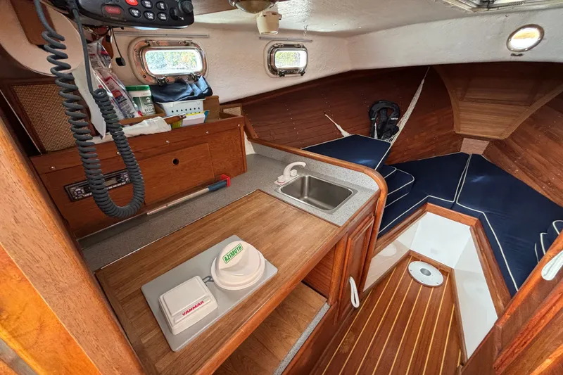 Slide: The Image of Interior of 1993 Webbers Cove Pemaquid Beach 26 boat with wooden cabinetry and compact kitchenette. - 16