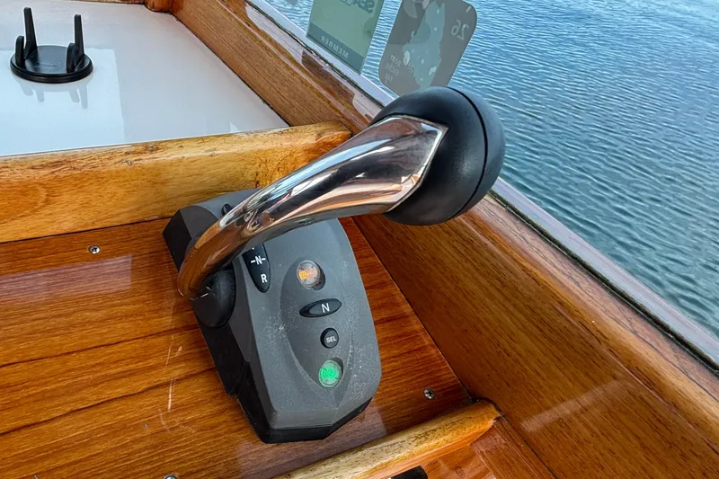 Slide: The Image of Throttle control on 1993 Webbers Cove Pemaquid Beach 26 boat, with wooden dashboard and water view. - 27