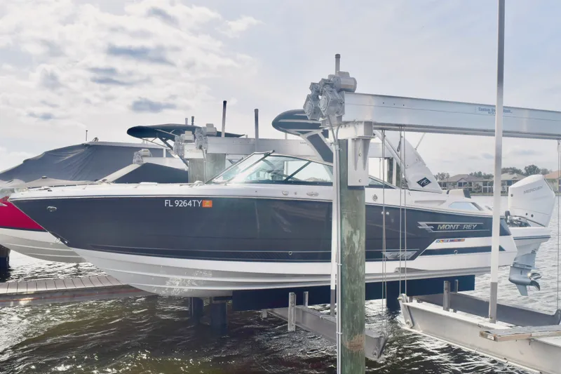 The Image of 2025 Monterey 275SS Super Sport boat on lift, docked by waterfront homes. - 0