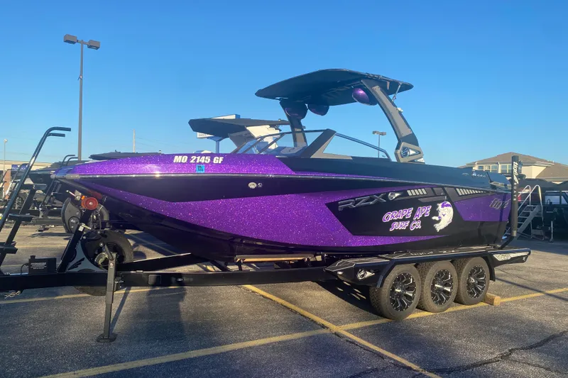 Slide: The Image of 2017 Tigé RZX3 boat with purple glitter finish on a trailer in a parking lot. - 25