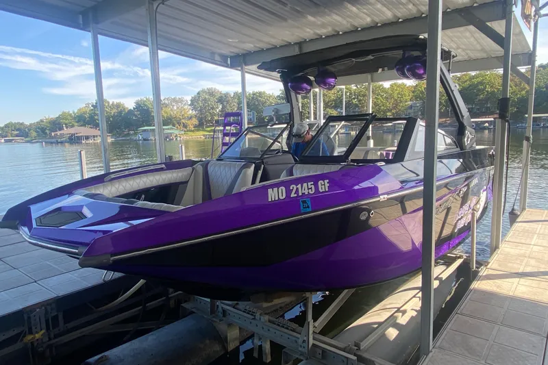 Slide: The Image of 2017 Tigé RZX3 boat in vibrant purple, docked at a lakeside marina. - 33