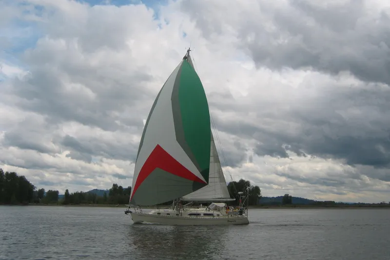 Slide: The Image of Sailboat Outbound 44/46 (2001) with colorful spinnaker on a cloudy day. - 60