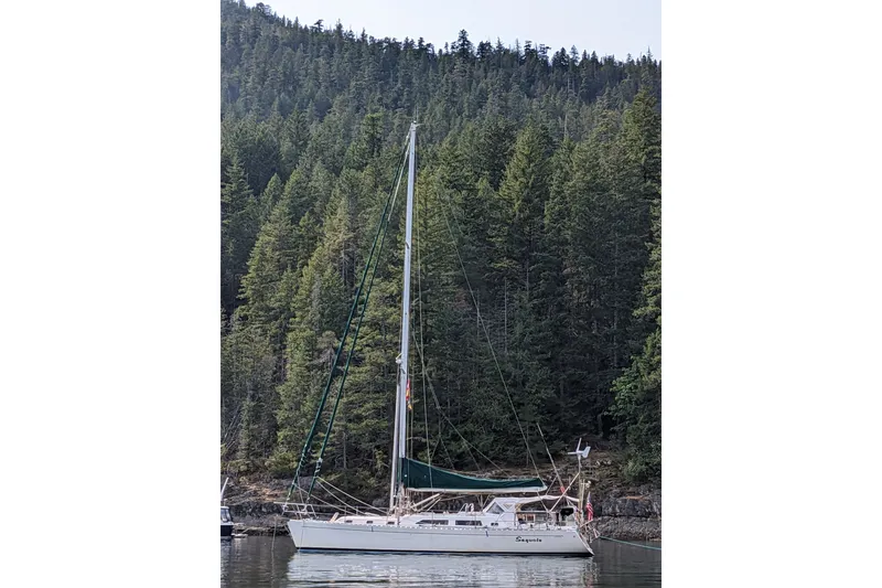 Slide: The Image of Sailboat "Outbound 44/46" from 2001 anchored near forested shoreline. - 57