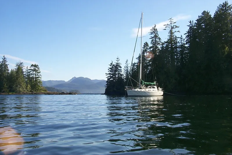Slide: The Image of Sailboat Outbound 44/46 (2001) anchored in scenic forested bay with mountains. - 62