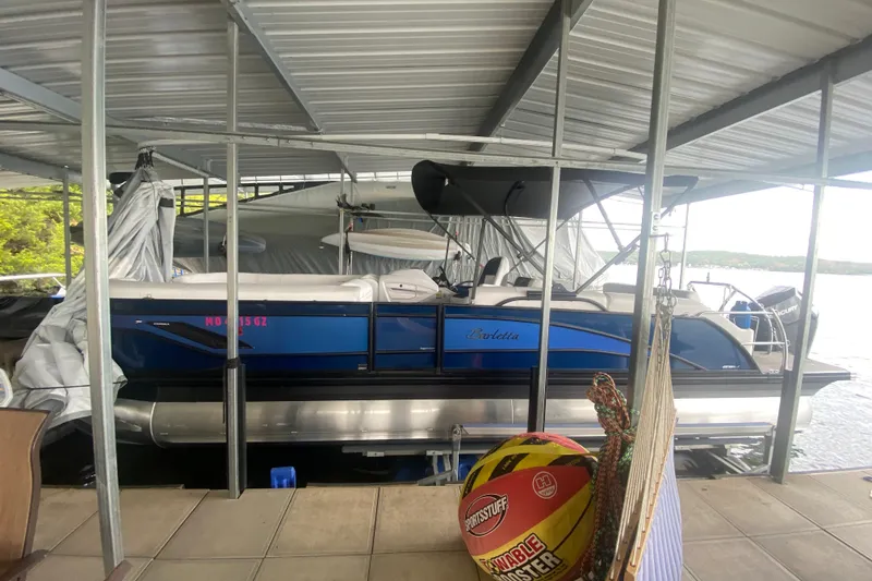 Slide: The Image of 2024 Barletta Corsa 25U pontoon boat docked under a covered marina. - 5