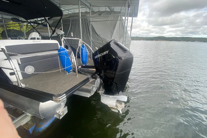 Slide: The Image of 2024 Barletta Corsa 25U pontoon boat with Mercury outboard motor docked on a lake. - 7
