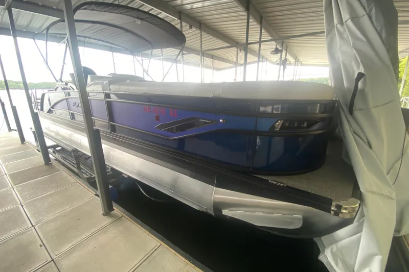 Slide: The Image of 2024 Barletta Corsa 25U pontoon boat docked under a covered marina. - 32