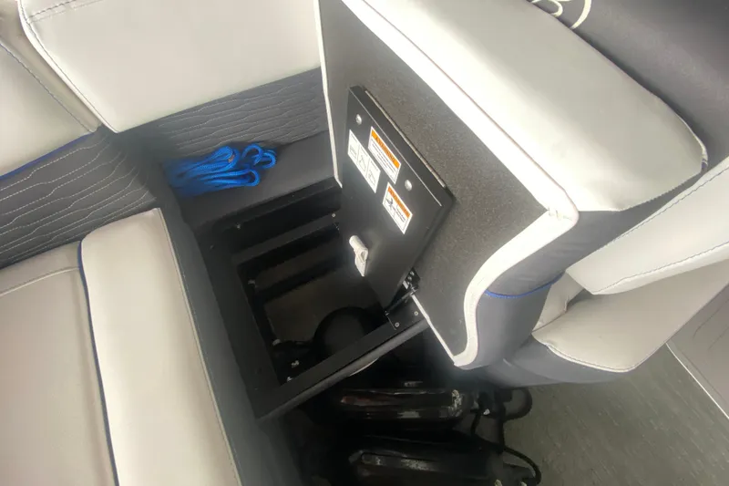 Slide: The Image of 2024 Barletta Corsa 25U boat seat storage compartment with blue rope and safety labels. - 15