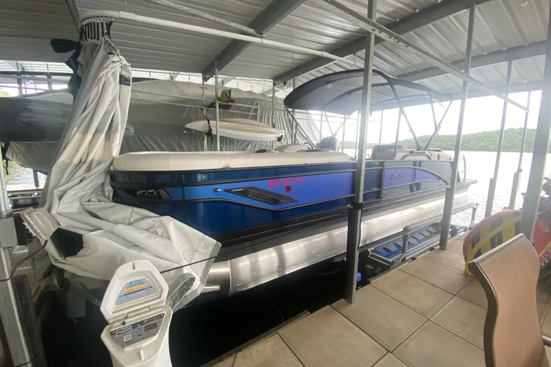 Slide: The Image of 2024 Barletta Corsa 25U pontoon boat docked under a covered marina. - 14
