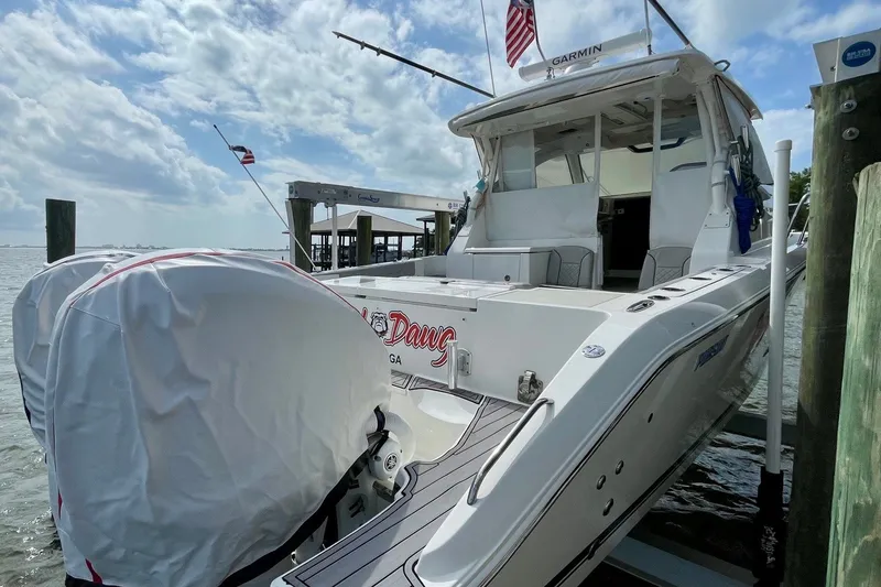 Slide: The Image of 2022 Pursuit OS 355 Offshore boat docked, featuring twin covered engines and a spacious deck. - 12