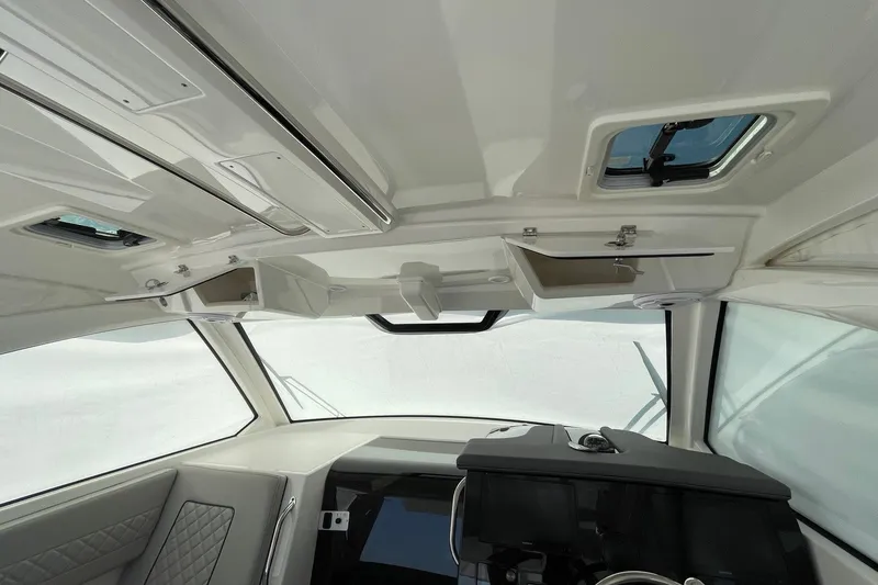 Slide: The Image of Interior view of 2022 Pursuit OS 355 Offshore boat, featuring helm and overhead storage. - 21
