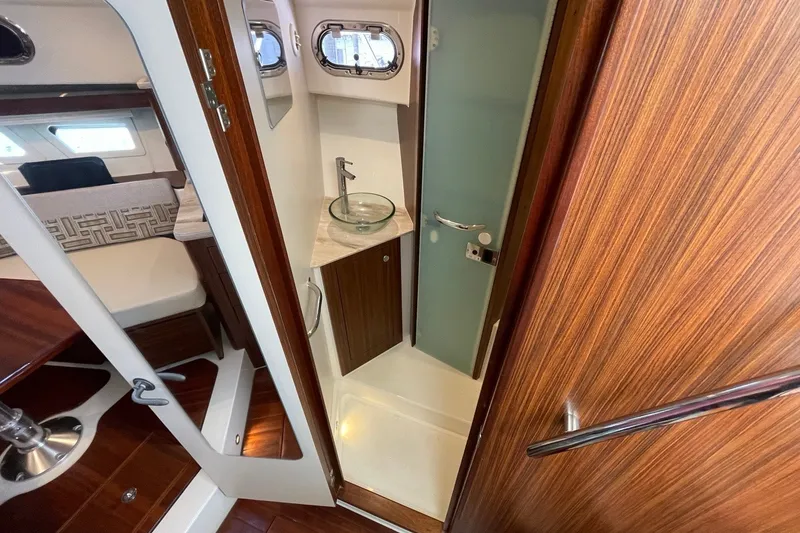 Slide: The Image of Interior of 2022 Pursuit OS 355 Offshore boat, featuring a compact bathroom with wood accents. - 32