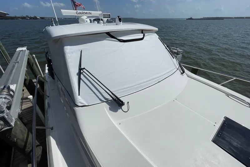 Slide: The Image of 2022 Pursuit OS 355 Offshore boat docked by the water, featuring a covered windshield. - 5