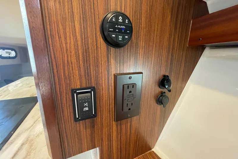 Slide: The Image of 2022 Pursuit OS 355 Offshore interior with wood paneling, electrical outlets, and control panel. - 38