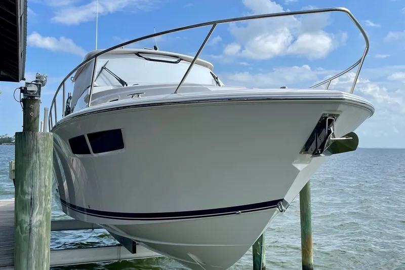 Slide: The Image of 2022 Pursuit OS 355 Offshore boat docked by the water under a clear blue sky. - 3