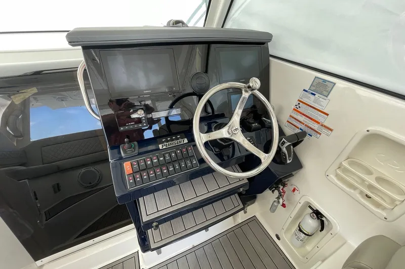 Slide: The Image of 2022 Pursuit OS 355 Offshore helm with steering wheel, controls, and navigation screens. - 26