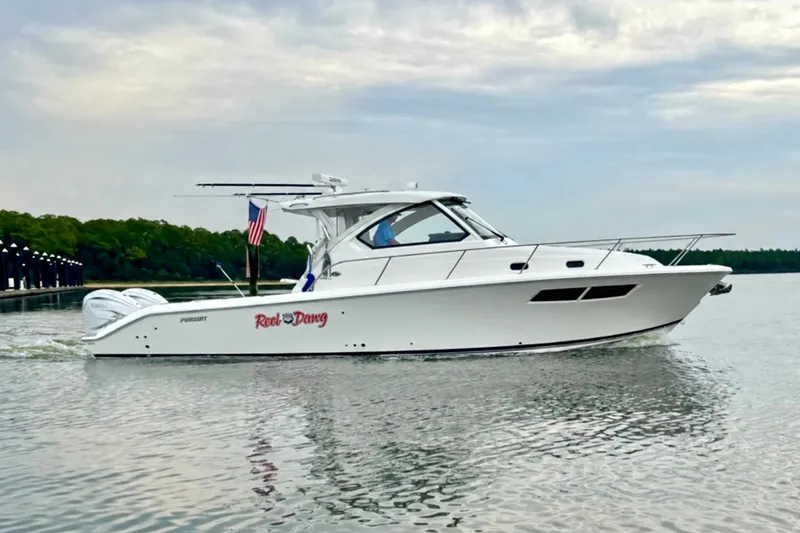 Slide: The Image of 2022 Pursuit OS 355 Offshore boat cruising on calm water with American flag. - 2
