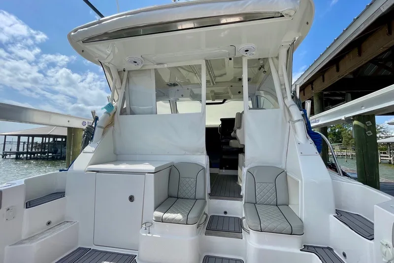 Slide: The Image of 2022 Pursuit OS 355 Offshore boat interior with seating, docked under blue sky. - 16