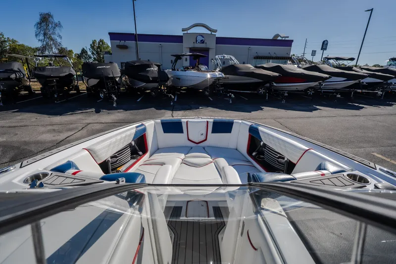 Slide: The Image of 2016 Nautique Super Air Nautique G23 boat interior at dealership, surrounded by covered boats. - 24