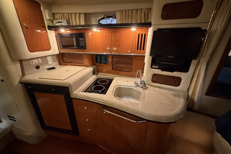 Slide: The Image of 1999 Sea Ray 340 Sundancer galley with wood cabinetry, sink, stove, and microwave. - 31