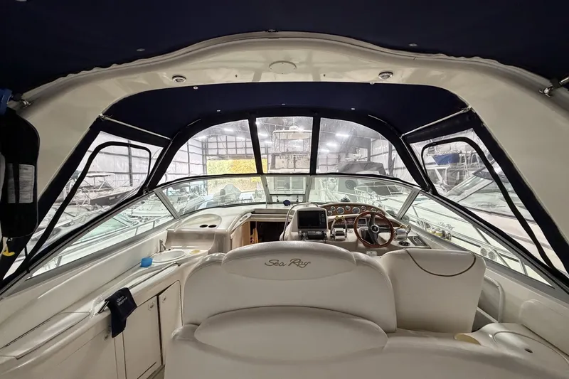 Slide: The Image of 1999 Sea Ray 340 Sundancer cockpit with helm, steering wheel, and seating in a marina setting. - 18