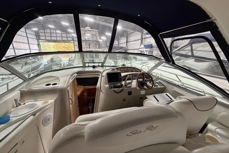 Slide: The Image of 1999 Sea Ray 340 Sundancer boat interior with helm, steering wheel, and dashboard in a marina. - 19