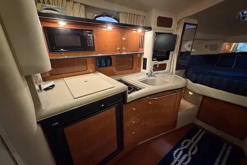 Slide: The Image of 1999 Sea Ray 340 Sundancer interior with kitchenette, microwave, sink, and cozy sleeping area. - 29