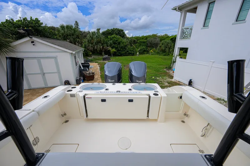 Slide: The Image of 2019 Cobia 301 Center Console boat with twin engines, docked near a house and garage. - 30