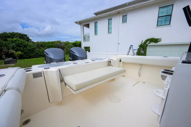 Slide: The Image of 2019 Cobia 301 Center Console boat with dual engines, parked near a house. - 27