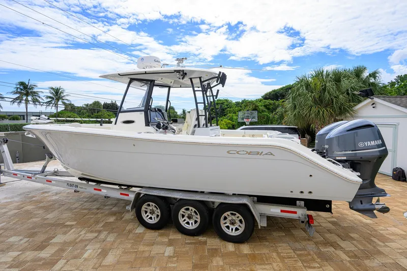 Slide: The Image of 2019 Cobia 301 Center Console boat on trailer with Yamaha engines, parked outdoors. - 12