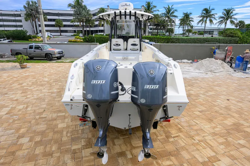 Slide: The Image of 2019 Cobia 301 Center Console boat with twin Yamaha 300 engines, parked on brick pavement. - 2