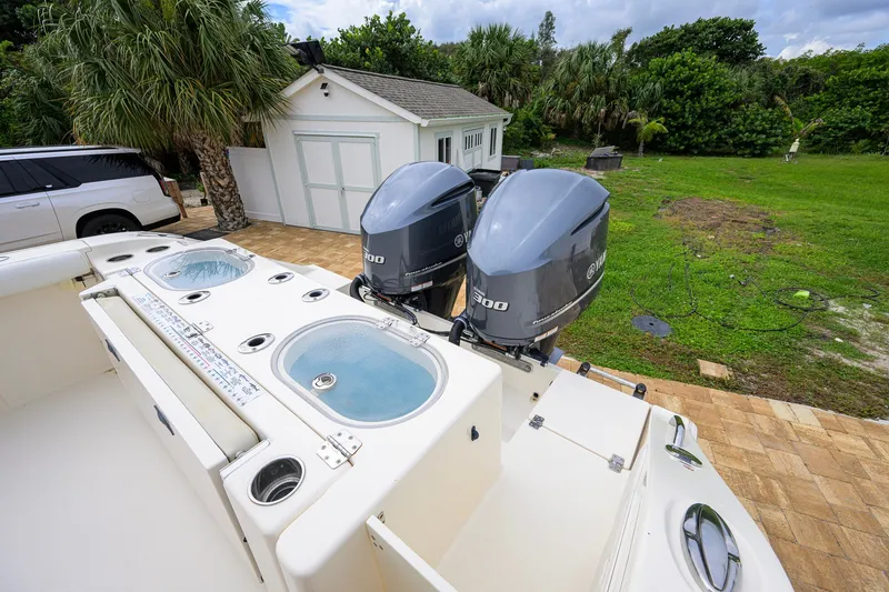 Slide: The Image of 2019 Cobia 301 Center Console boat with dual Yamaha engines, parked near a garage. - 16