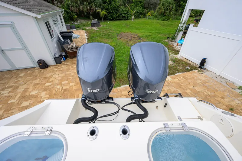 Slide: The Image of 2019 Cobia 301 Center Console with twin Yamaha 300 engines, docked near a garden. - 15