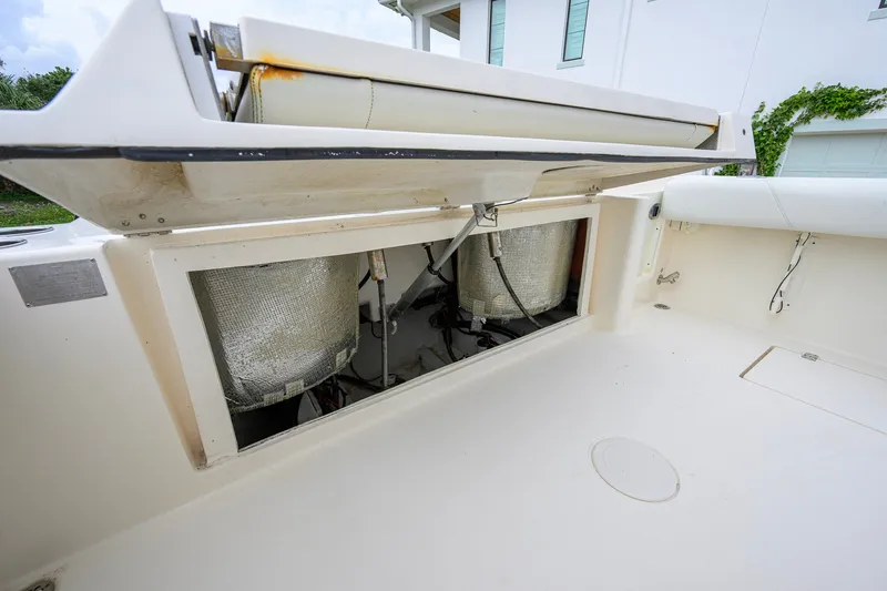 Slide: The Image of 2019 Cobia 301 Center Console boat storage compartment with open hatch, revealing interior components. - 26