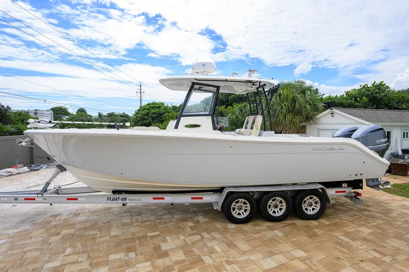Slide: The Image of 2019 Cobia 301 Center Console boat on trailer, parked outdoors. - 1
