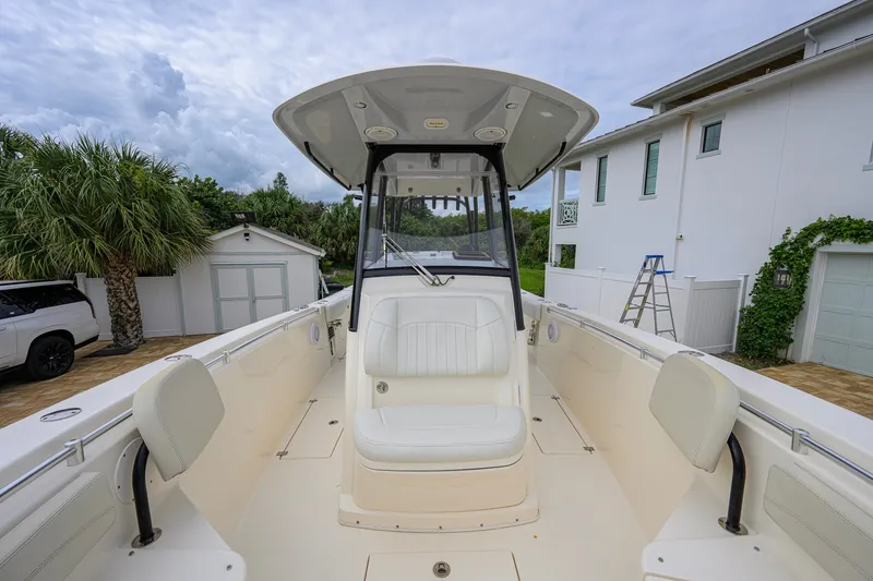 Slide: The Image of 2019 Cobia 301 Center Console boat docked near a white house and palm trees. - 43