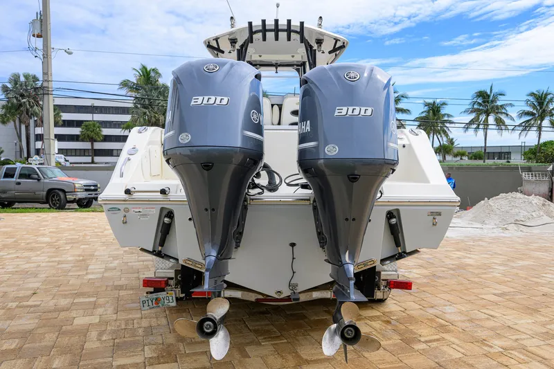Slide: The Image of 2019 Cobia 301 Center Console boat with dual Yamaha 300 engines, parked on a paved area. - 8