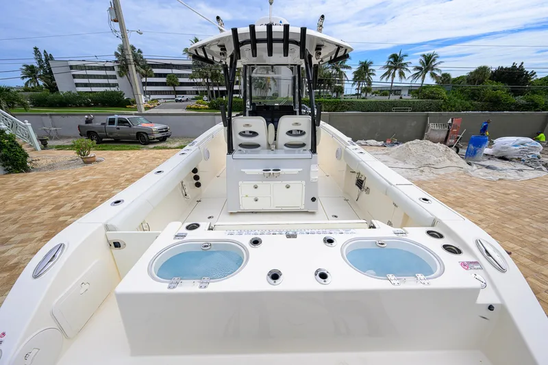 Slide: The Image of 2019 Cobia 301 Center Console boat with spacious deck and dual livewells, parked outdoors. - 23