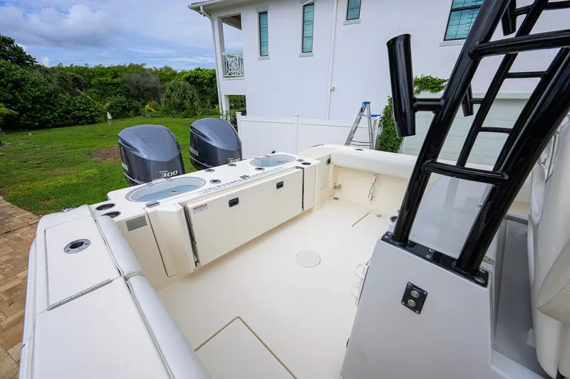Slide: The Image of 2019 Cobia 301 Center Console boat with dual Yamaha engines, parked near a white house. - 31